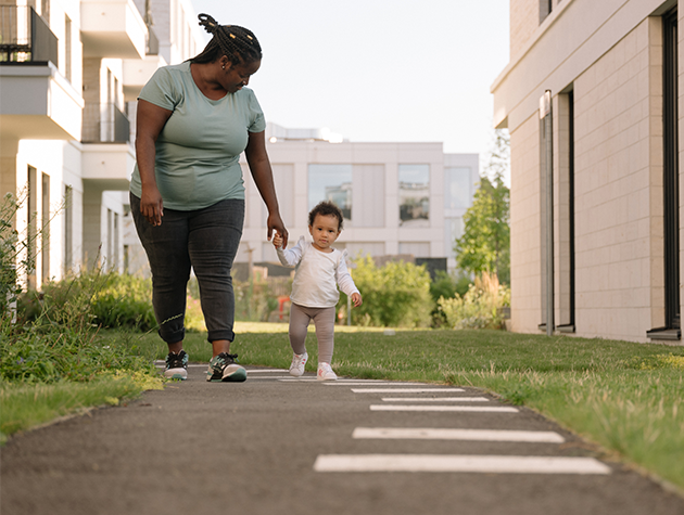 Mother walking with her young child outside.